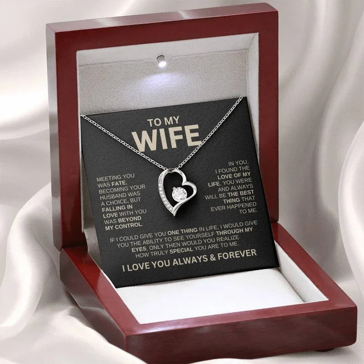 Heart-shaped necklace in a jewelry box with a sentimental message card on a white fabric background
