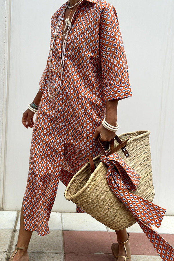 Person wearing a patterned dress holding a straw bag with a scarf draped over it against a white wall.