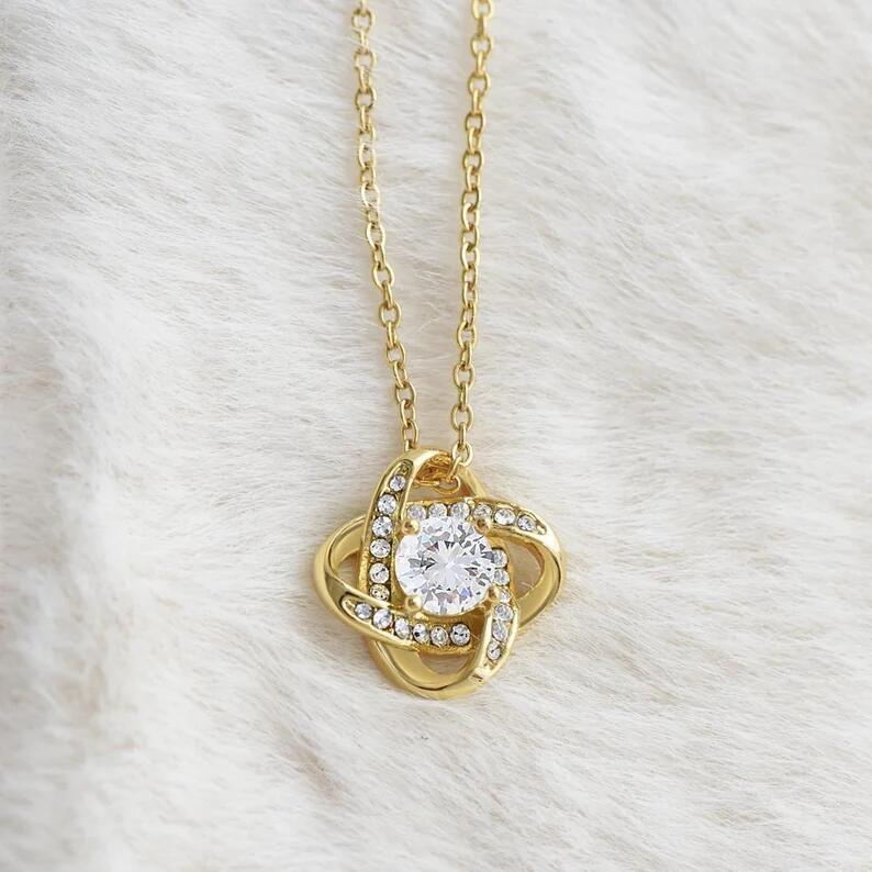 Gold necklace with a diamond pendant on a white fur background