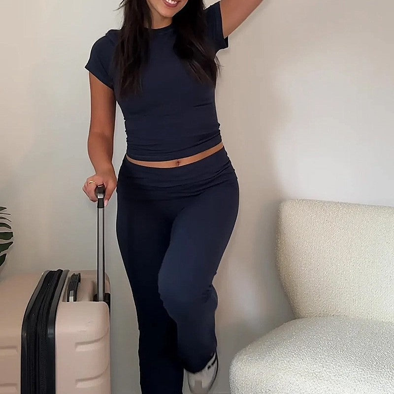 Person in navy outfit standing next to a suitcase indoors
