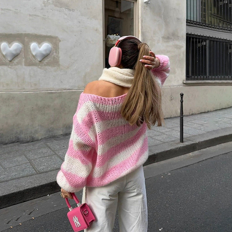 Person wearing a pink and white striped sweater and pink headphones, walking on a street.
