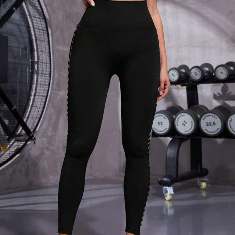 Person wearing black leggings in a gym setting with weights in the background