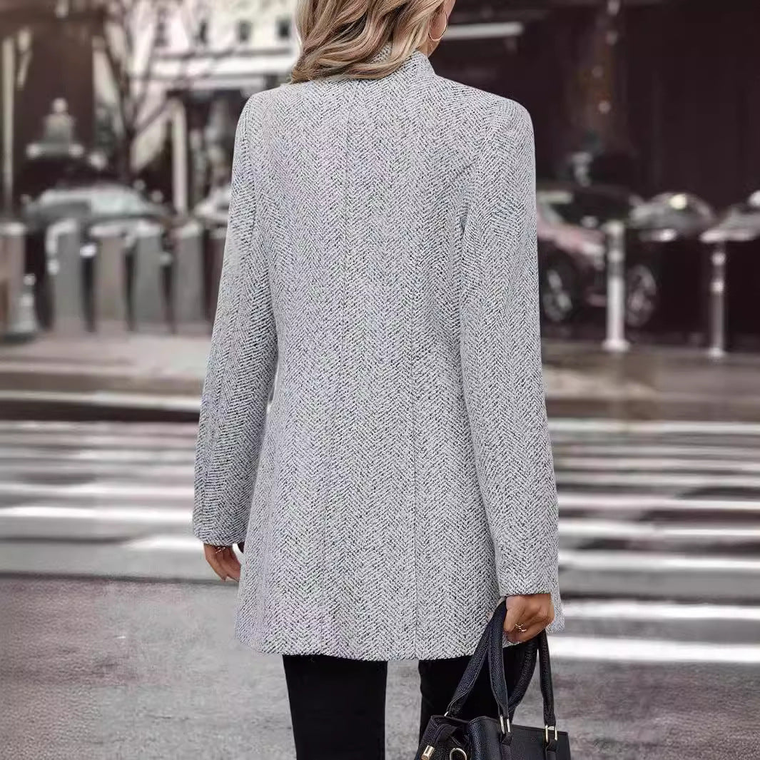 Person wearing a gray coat crossing a street with blurred background