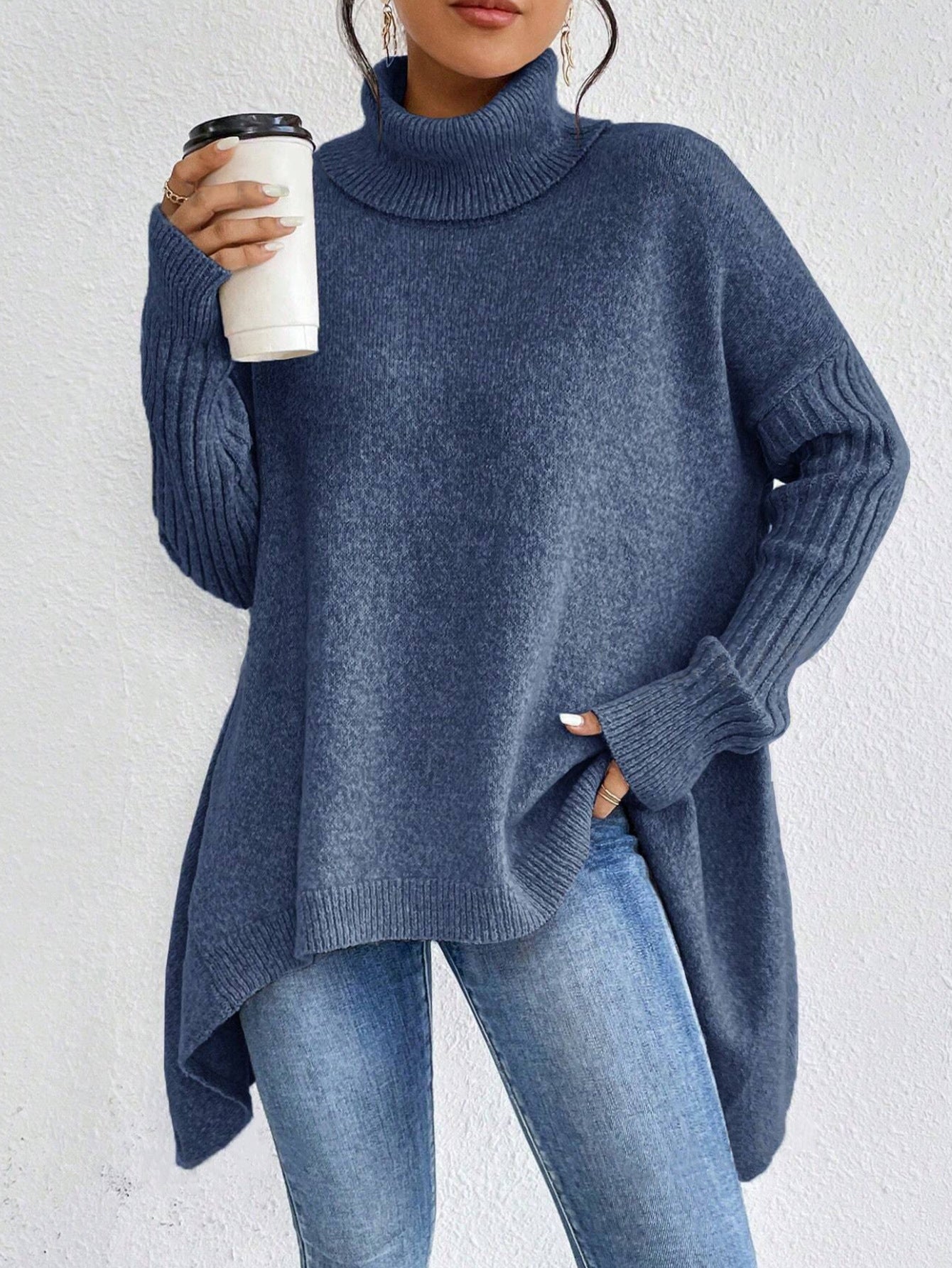 Person wearing a blue sweater holding a coffee cup against a white background