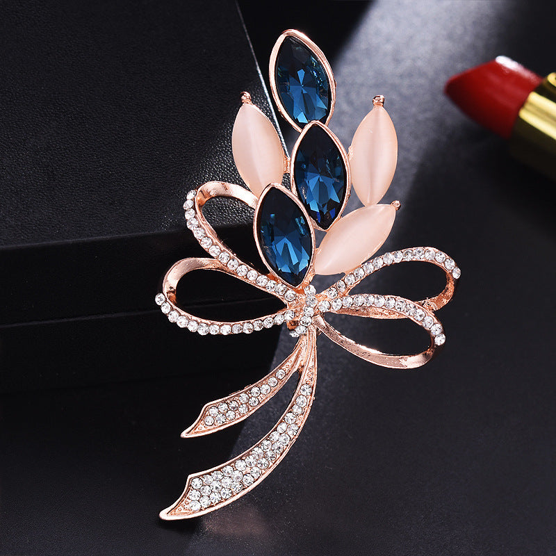 Decorative brooch with blue gemstones and rose gold accents on a dark background