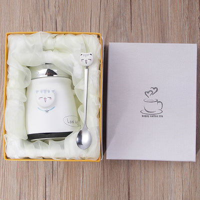 White ceramic mug with lid and spoon in a decorative box on a wooden surface