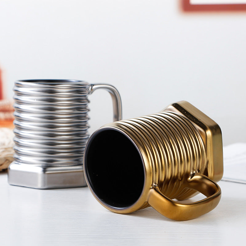 Gold and silver mugs on a white surface with a blurred background