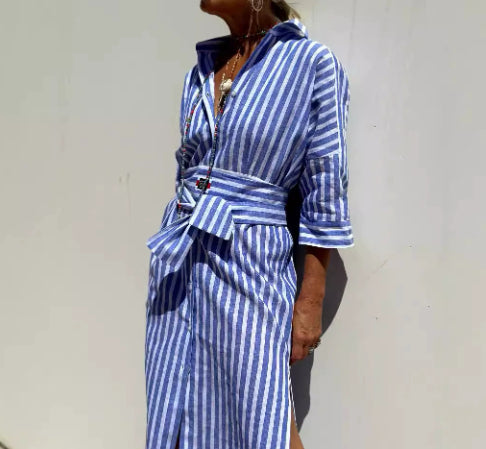 Person wearing a blue and white striped dress against a plain background