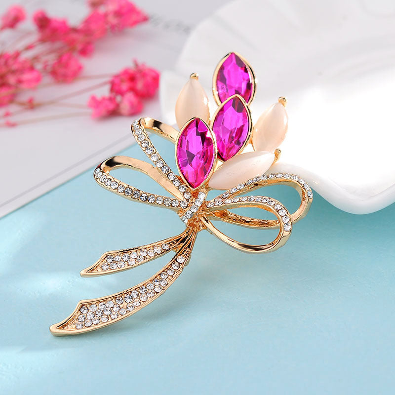 Decorative brooch with pink gemstones and gold accents on a light blue background