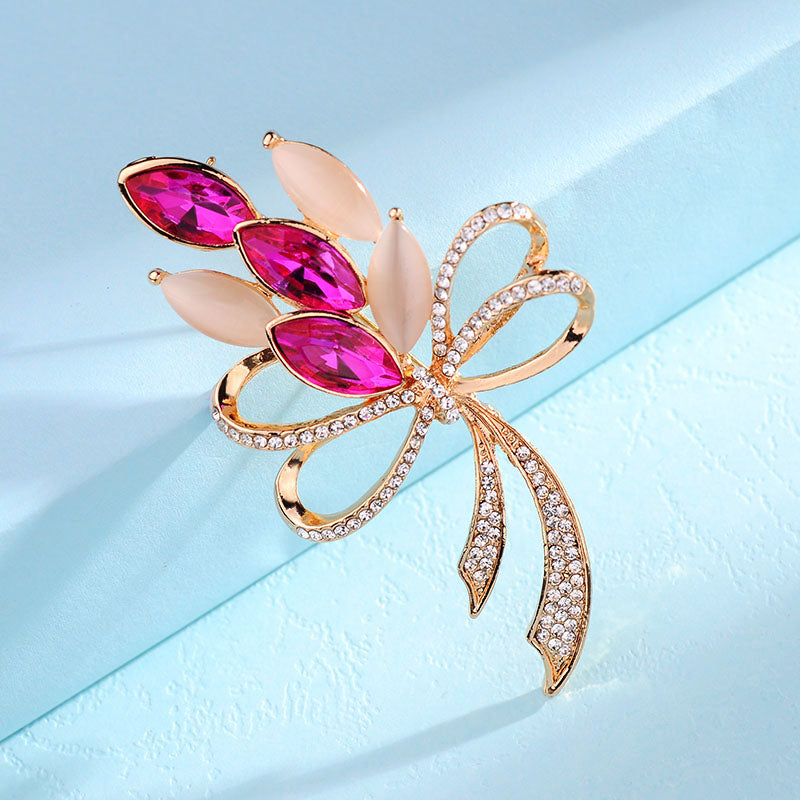 Decorative brooch with pink gemstones and gold accents on a light blue background