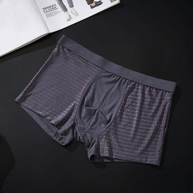 Gray boxer briefs on a dark surface with an open magazine in the background