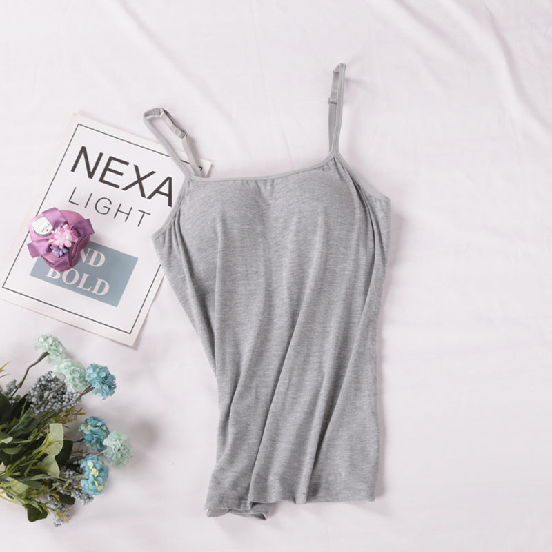Gray slip dress on a white surface with a book and flowers.