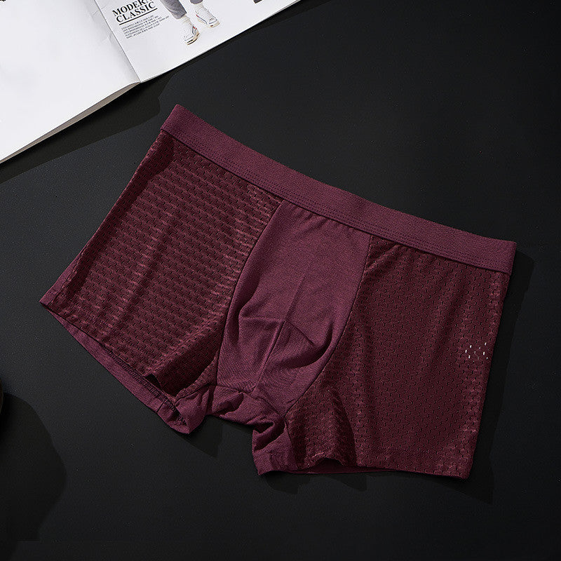Maroon boxer briefs on a dark surface with a magazine in the background
