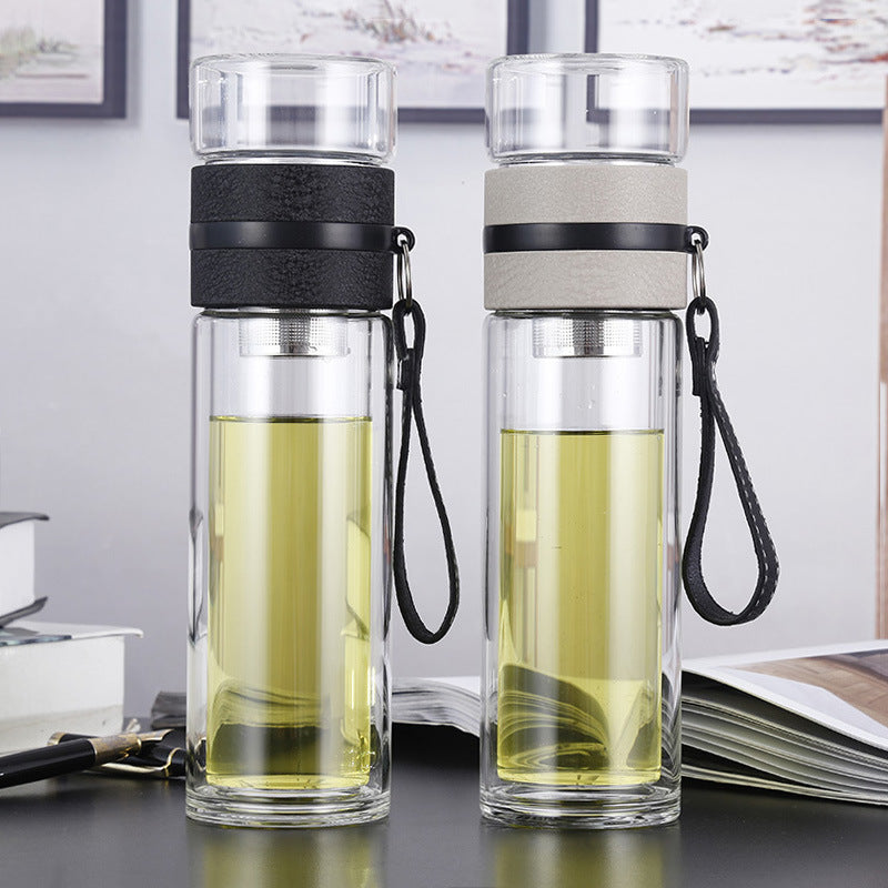 Two glass water bottles with black and gray lids on a desk.