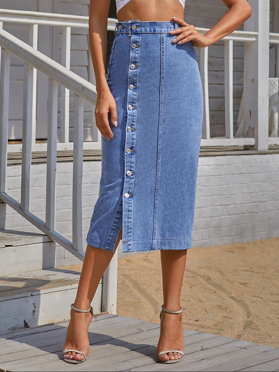 Woman wearing a light blue crop top and denim skirt standing on a wooden deck.