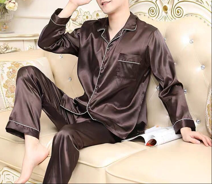 Man wearing brown satin pajamas sitting on a couch with decorative background