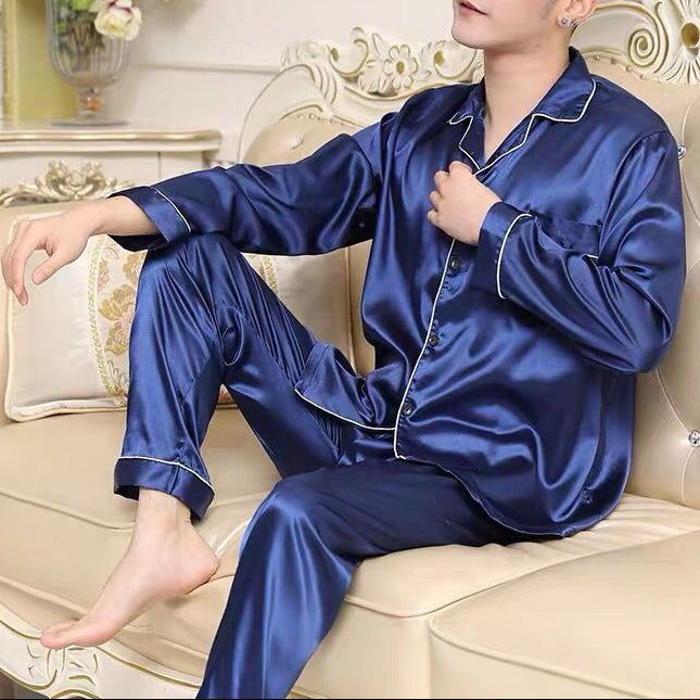 Man wearing blue satin pajamas sitting on a decorative couch.