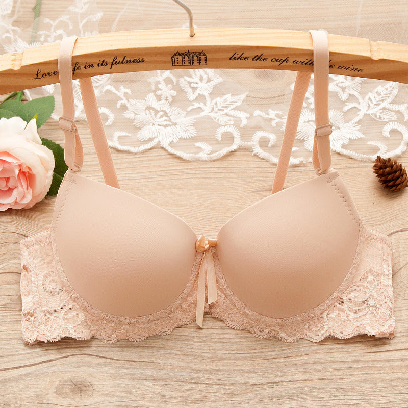 Beige bra with lace details on a wooden hanger against a lace curtain background