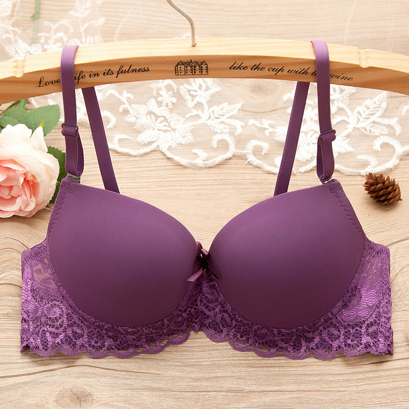 Purple bra with lace details on a wooden hanger with floral and decorative elements.