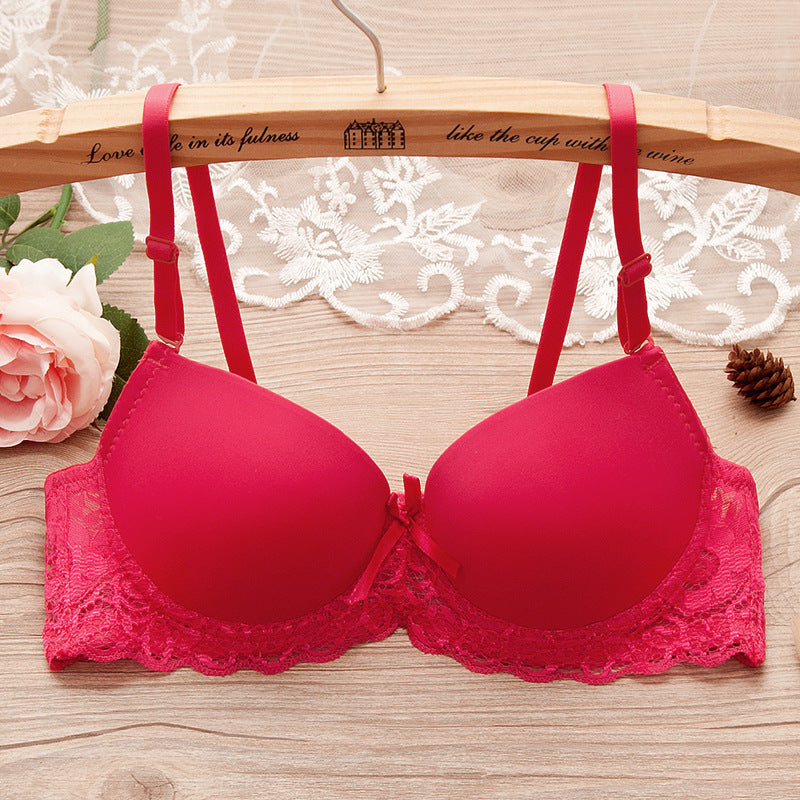 Red bra with lace details on a wooden hanger against a lace curtain background