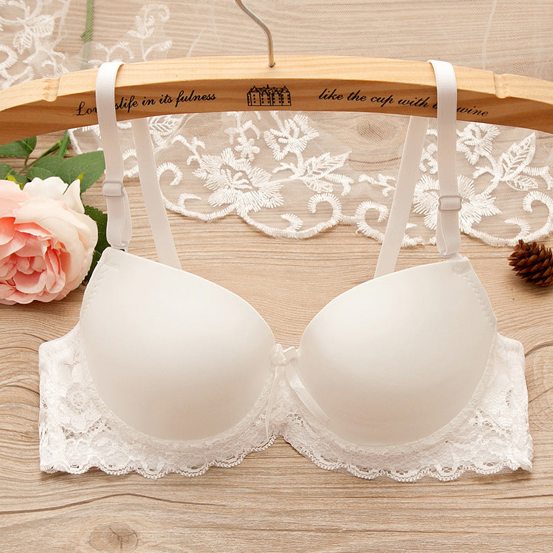 White bra with lace details on a wooden hanger against a floral background
