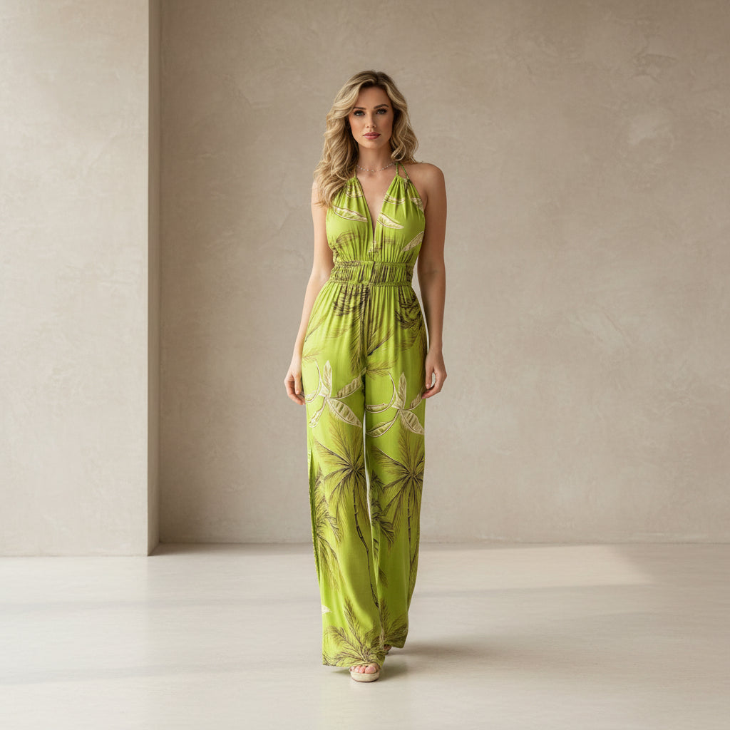 Woman wearing a green floral jumpsuit holding a straw bag indoors.