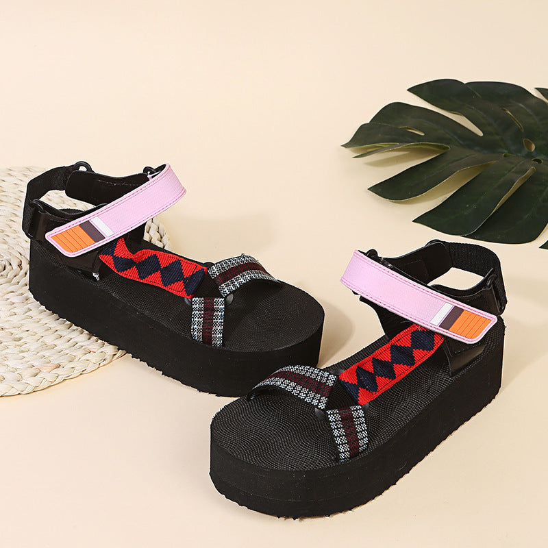 Black platform sandals with colorful straps on a beige background