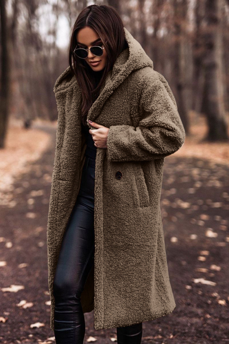 Woman wearing a long brown coat in a forest setting