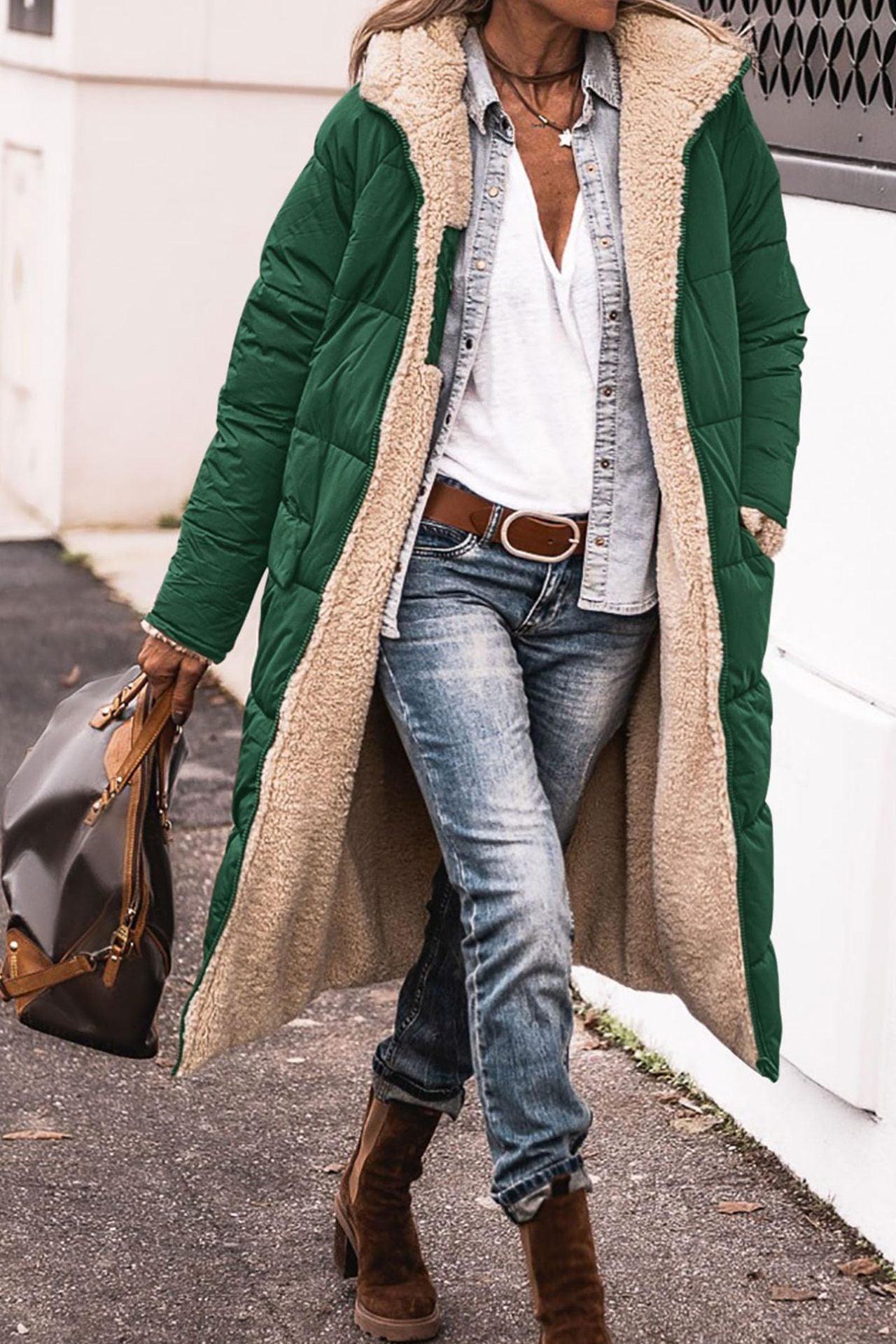 Person wearing a long green coat with beige lining, white shirt, blue jeans, and brown boots.