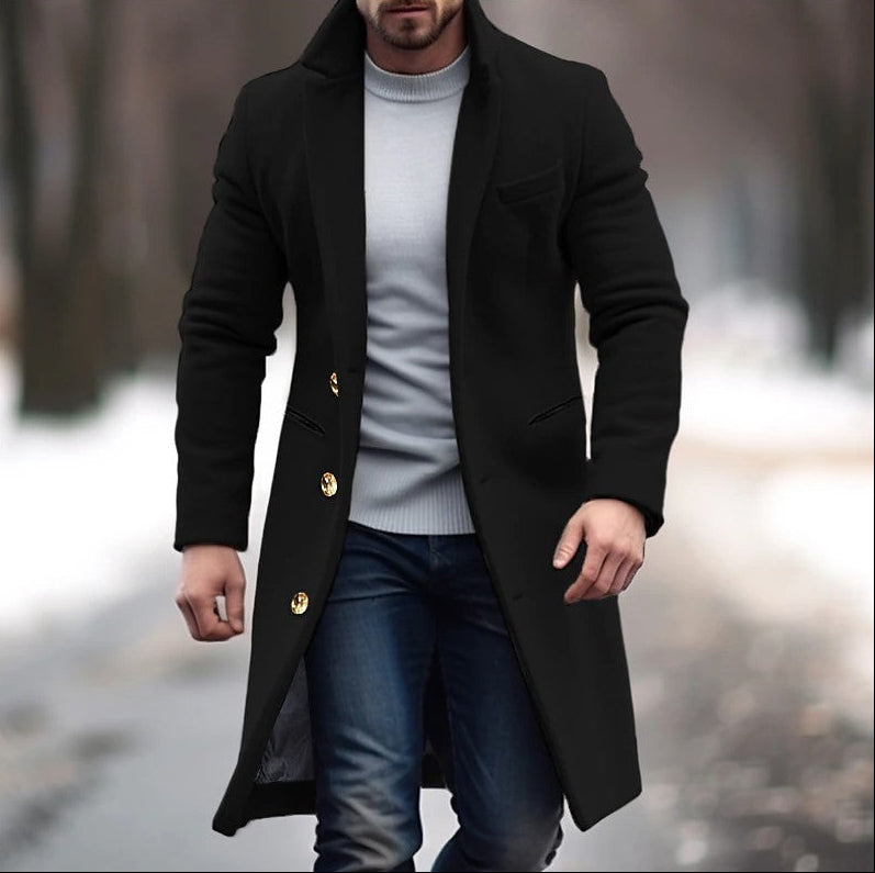 Man wearing a black coat with gold buttons in a blurred outdoor setting