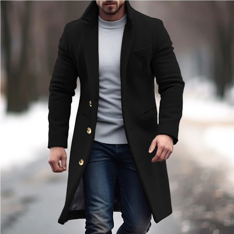 Man wearing a black coat with gold buttons in a blurred outdoor setting