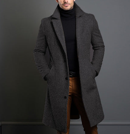Man wearing a gray overcoat against a dark background