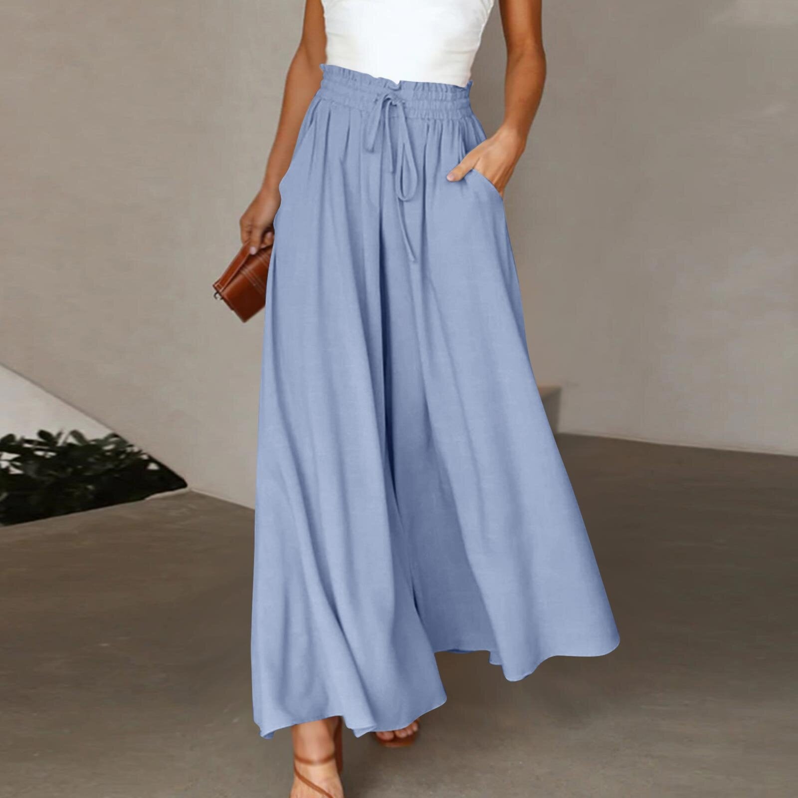 Woman wearing a long light blue skirt with a white top against a neutral background