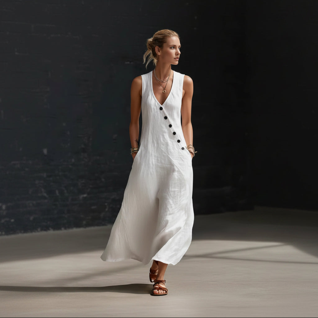 Woman wearing a white sleeveless dress with black buttons against a dark background