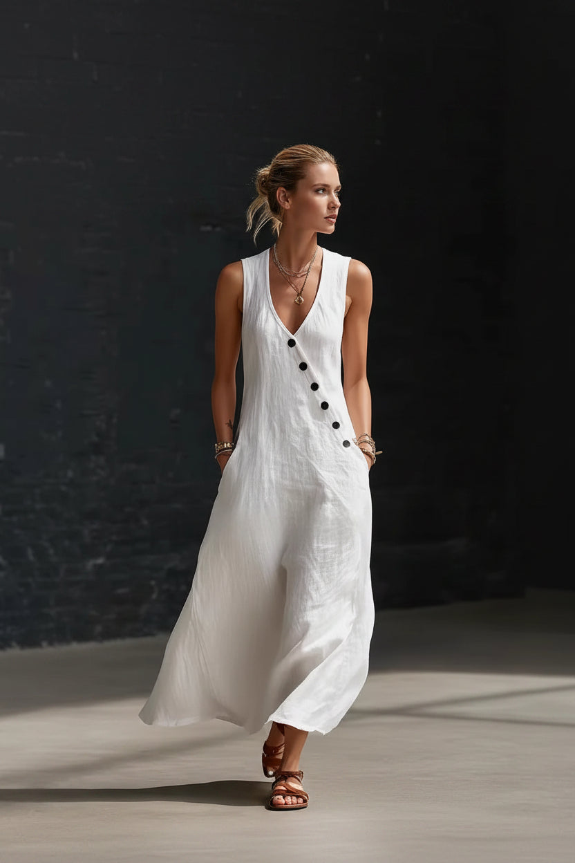 Woman wearing a white sleeveless dress with black buttons against a dark background