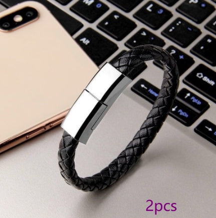 Black braided bracelet with metallic tag on a laptop keyboard