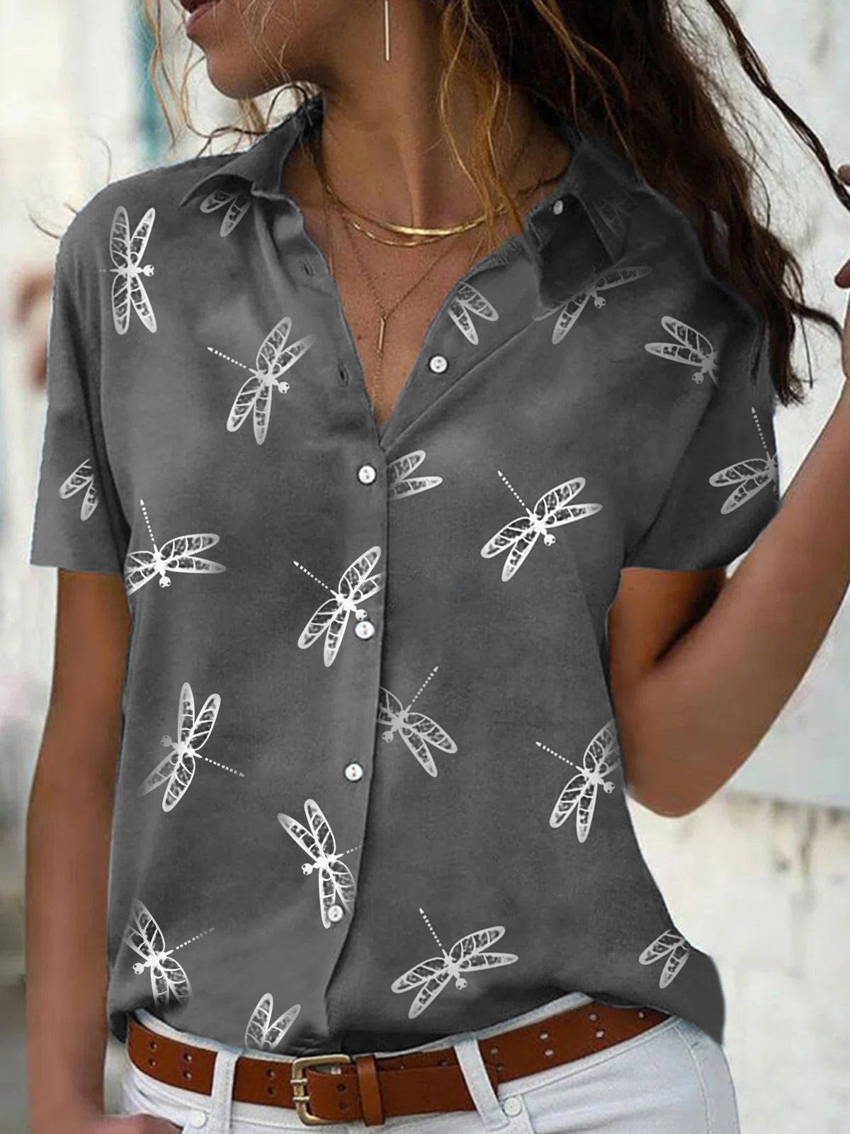 Woman wearing a gray shirt with white moth patterns, standing against a neutral background.
