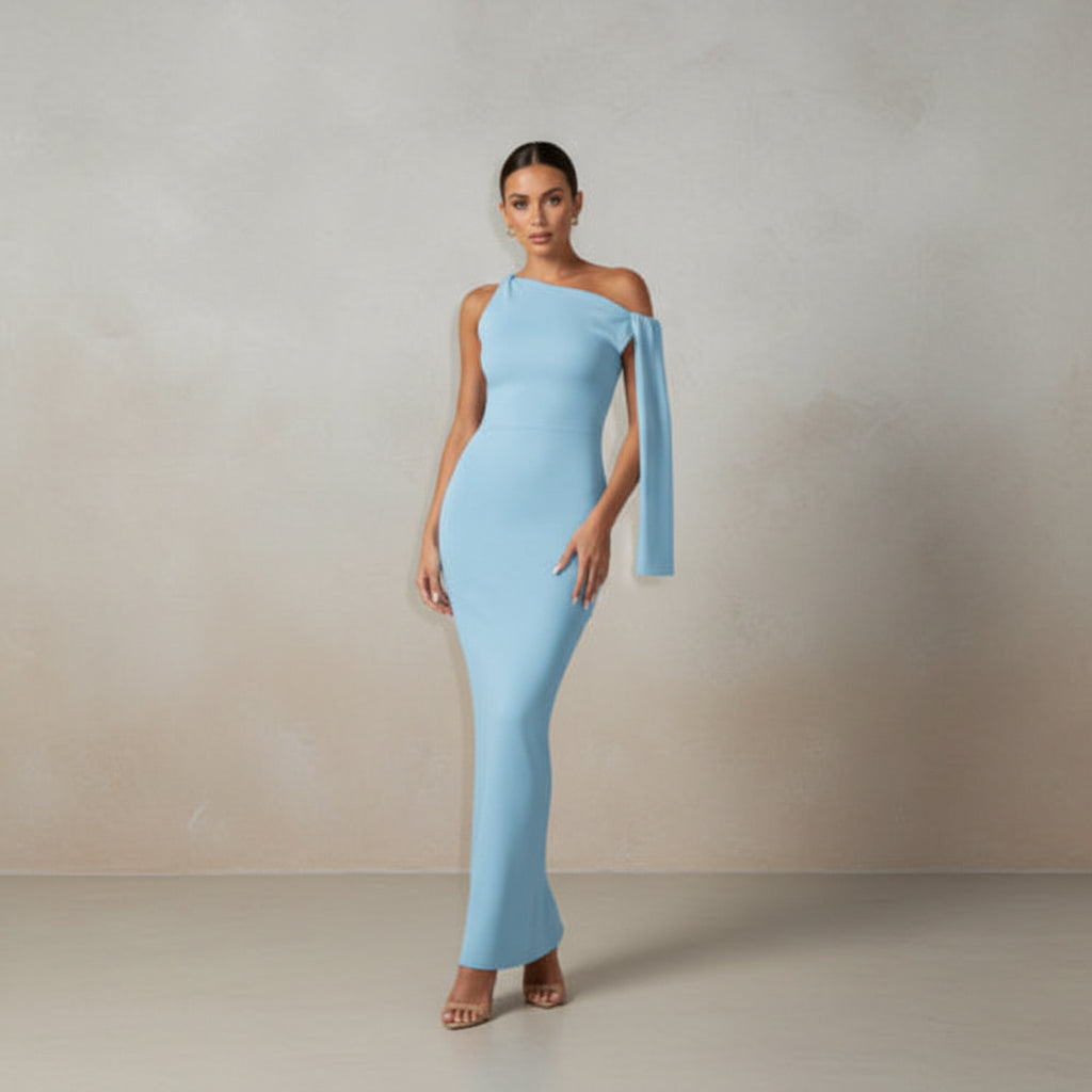 Woman in a light blue one-shoulder dress standing in an indoor setting.