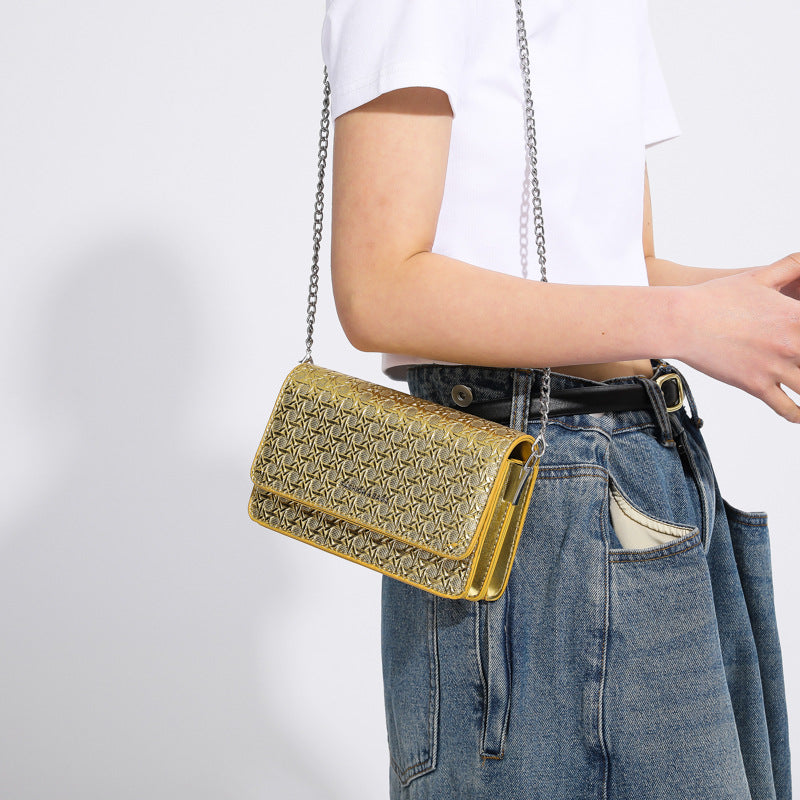 Person wearing a gold handbag with a chain strap on a white background