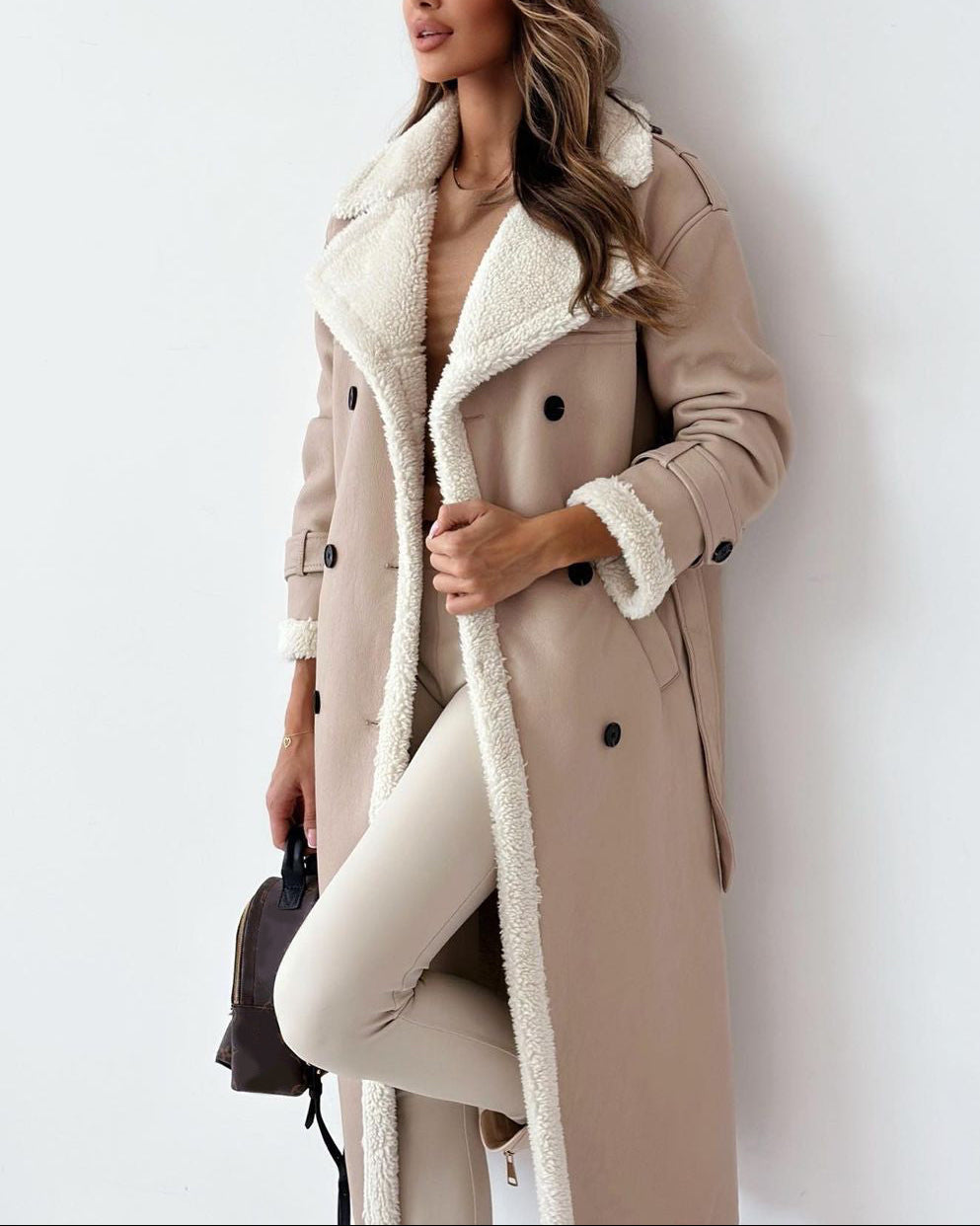 Woman wearing a beige coat with white fur trim against a white background