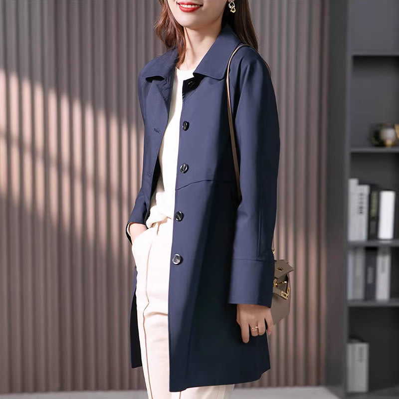 Woman wearing a navy blue coat with a neutral background