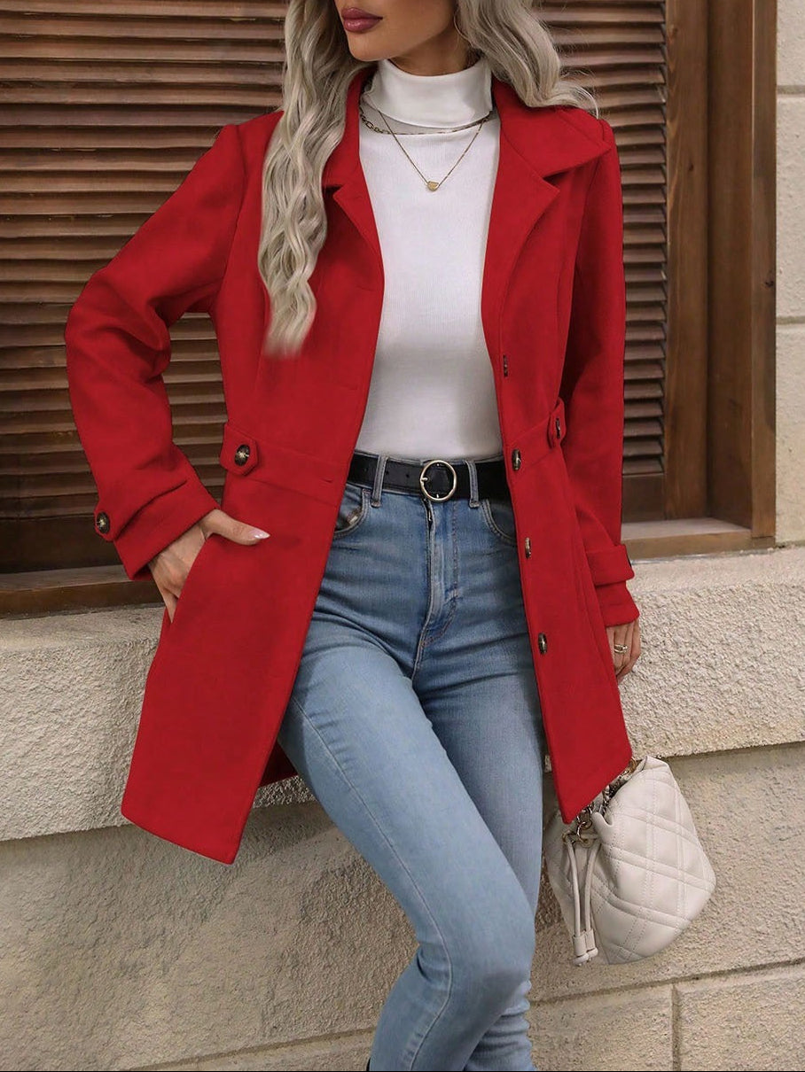 Woman wearing a red coat, white top, blue jeans, and beige hat against a wooden background.