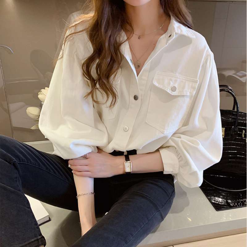 Person wearing a white shirt and dark jeans sitting on a kitchen counter.