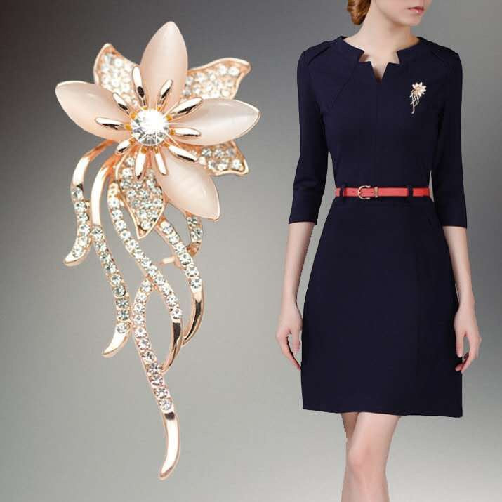 Floral brooch next to a woman wearing a navy dress with a matching brooch.