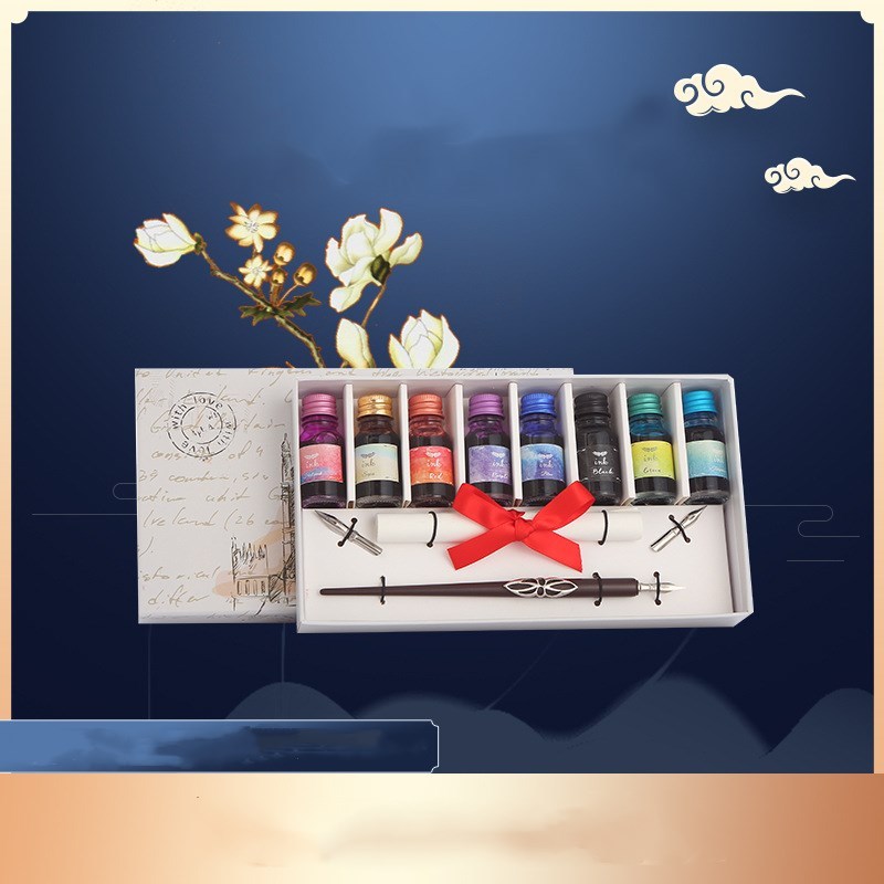 Set of ink bottles and calligraphy tools in a decorative box with a blue background and floral elements.