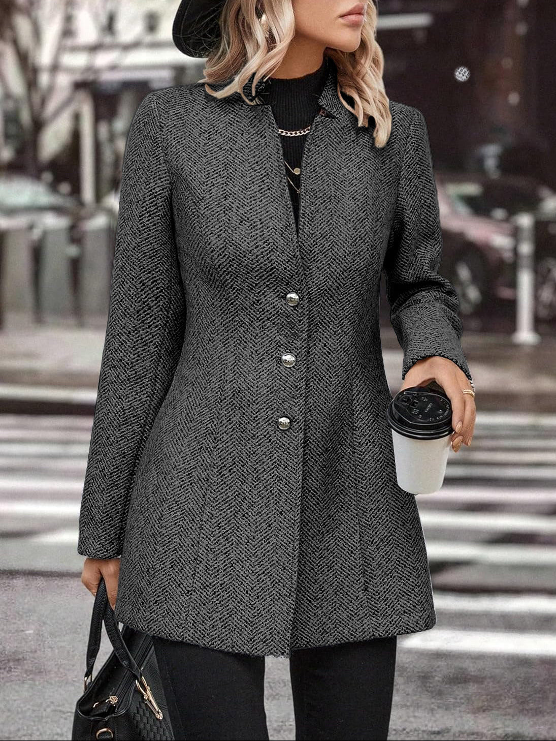 Woman in a gray coat holding a coffee cup on a city street