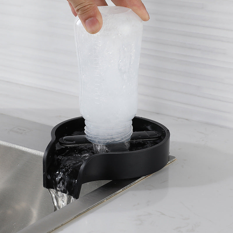 Person pouring water from a clear bottle into a black sink drain cover.