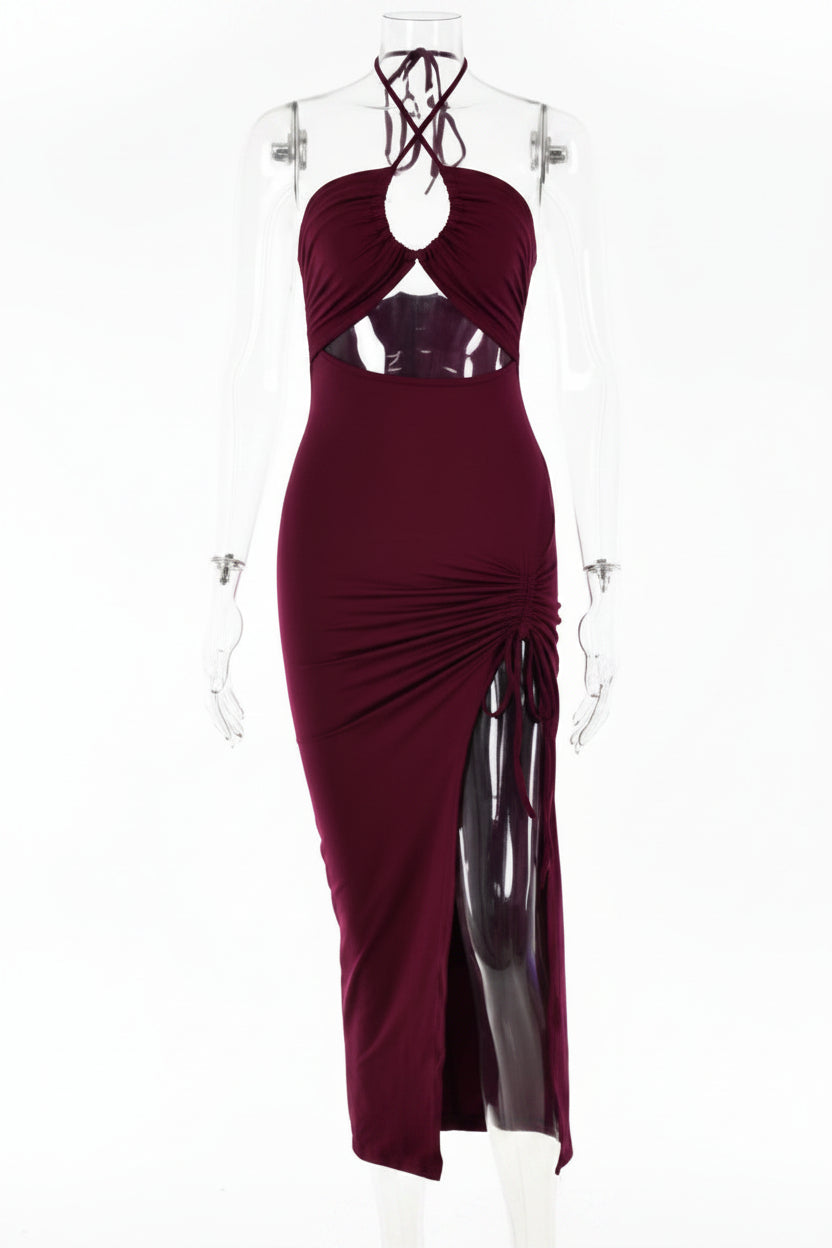A sleeveless halter-neck maxi dress in deep burgundy, displayed on a clear mannequin against a plain white background. The dress features a ruched bodice, a side slit, and a sheer mesh panel at the waist.