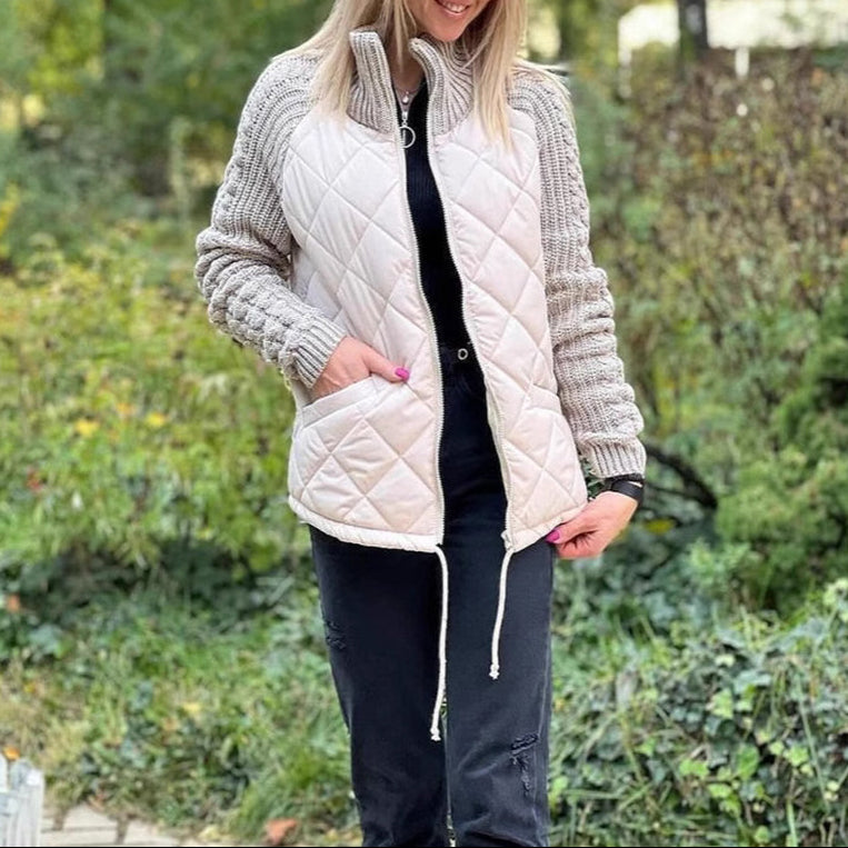 Woman wearing a white quilted vest over a gray knit cardigan in an outdoor setting.