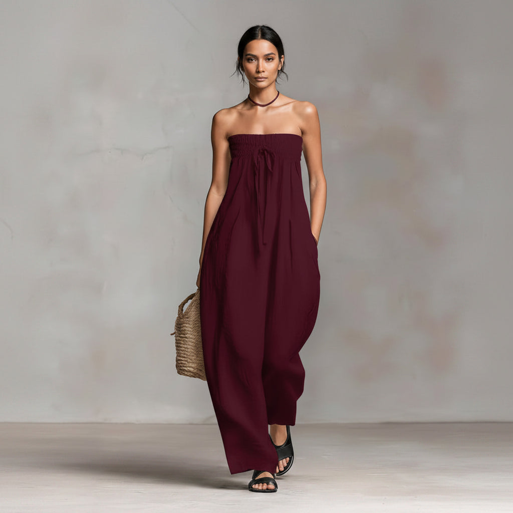 Woman wearing a strapless burgundy jumpsuit against a neutral background